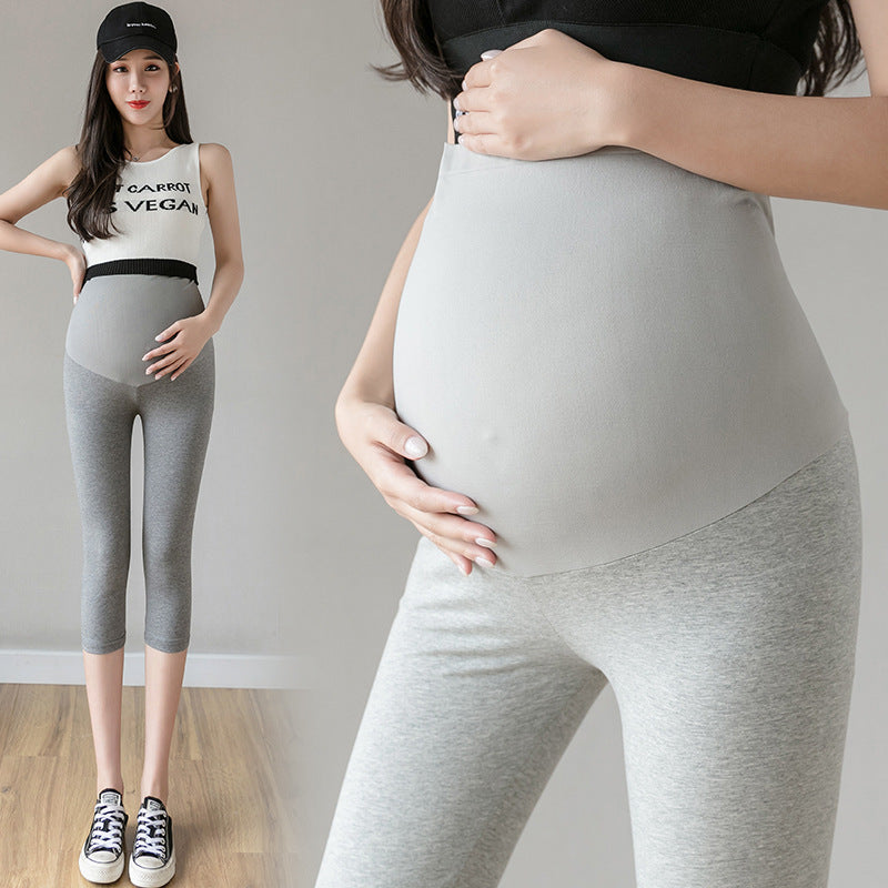 Pregnant woman in light gray cropped maternity yoga pants, showing comfortable fit and abdomen support, ideal for summer.